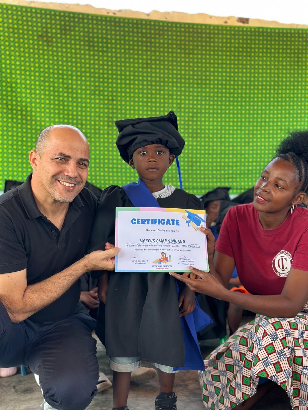 Aluno recebendo o certificado de conclusão da pré-escola em Nchalo