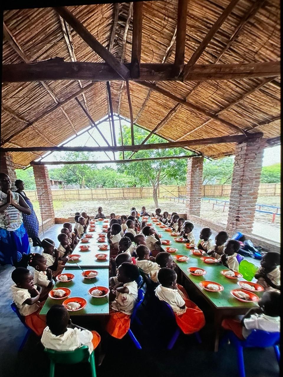 Crianças almoçando juntas no pátio coberto da pré-escola em Mafarinha