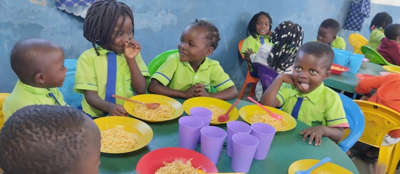 Crianças almoçando e brincando à mesa na pré-escola