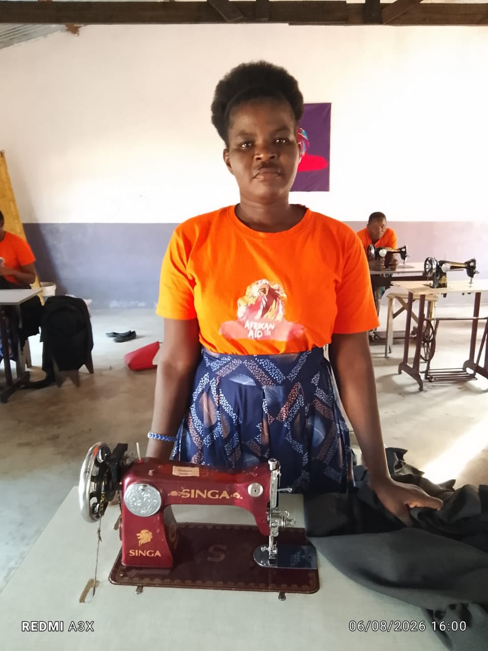 Viúva formada na escola de costura, ao lado de máquina de costura Singa